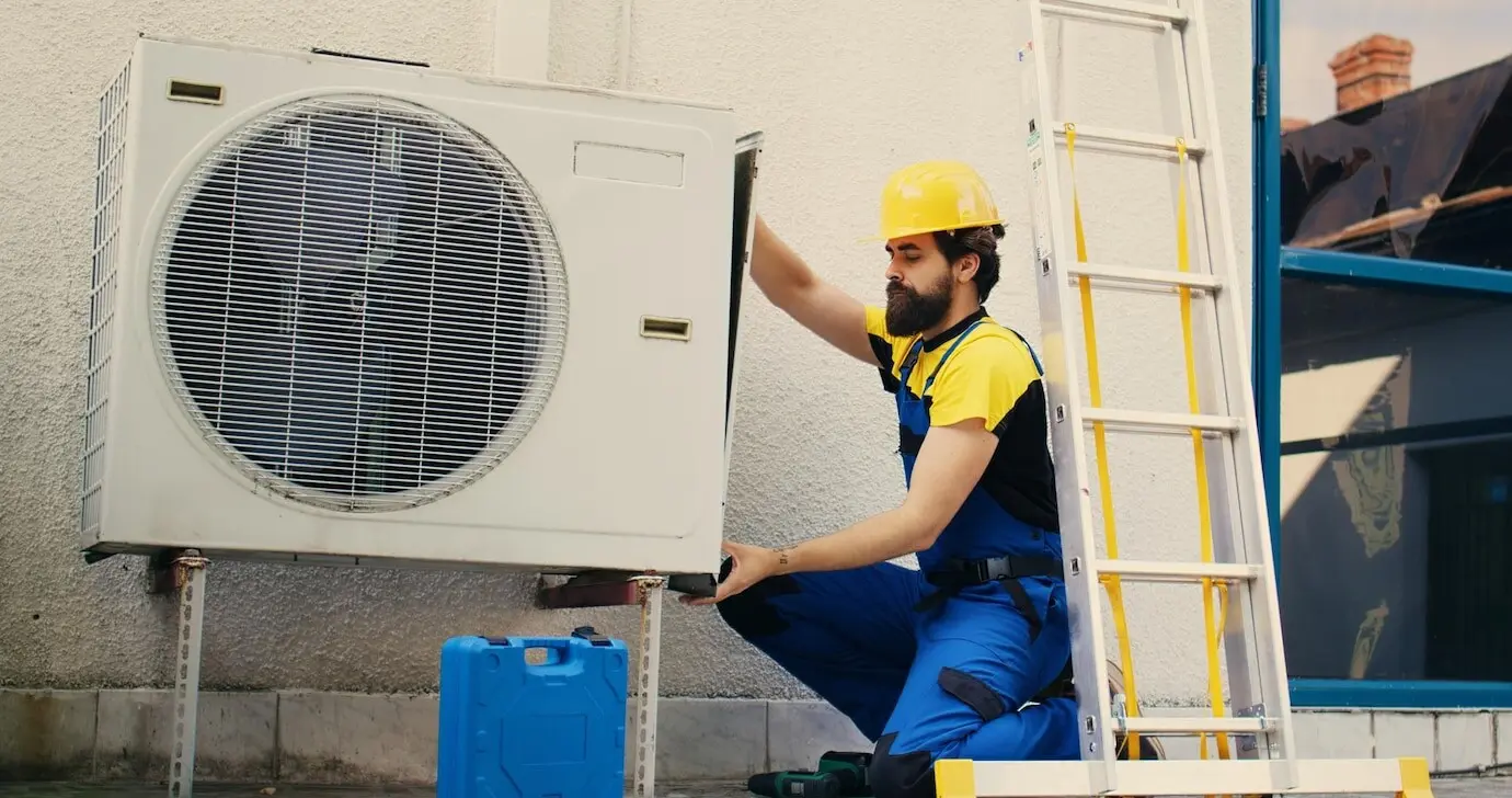 A worker is working on an air conditioner.