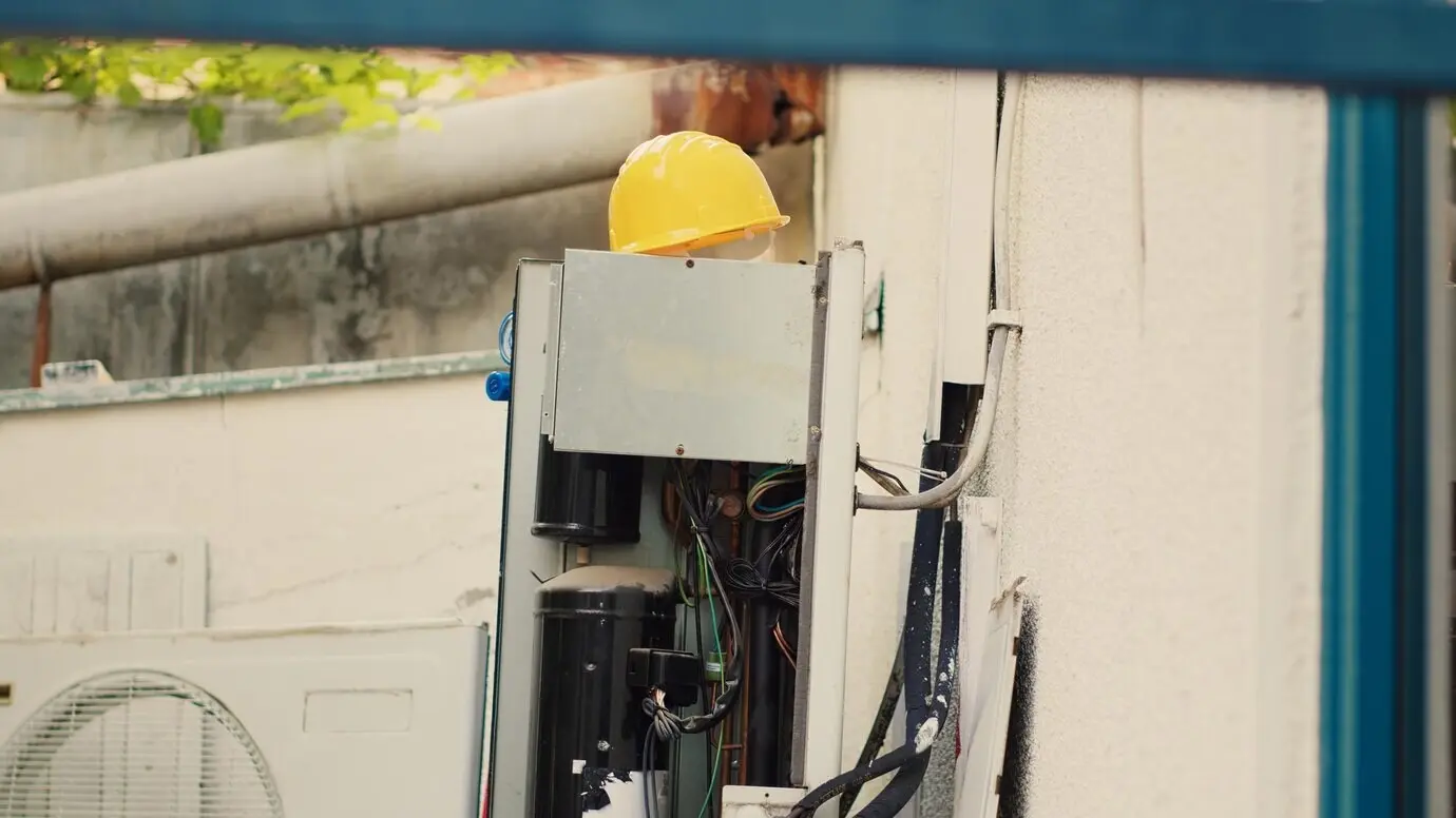 Dolly-in shot of an air conditioner with its side panel open before customer-commissioned repair work is performed on faulty wiring. The HVAC system is prepared to be fixed by a professional engineer.